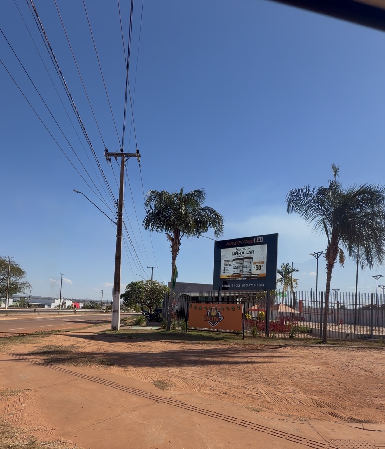 Vista aberta da avenida com o painel de LED ao longe e carros passando
